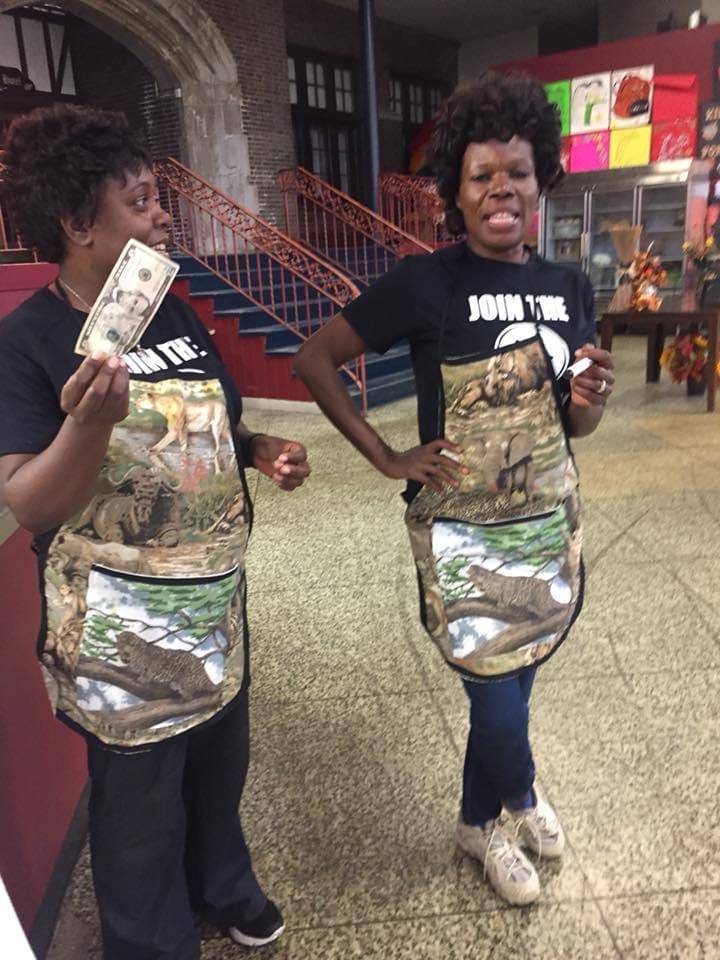 Chanda and her business partner are in camo aprons. Chanda is holding Stango Cuisine's first tip: a $5 bill. Photo by Stango Cuisine.