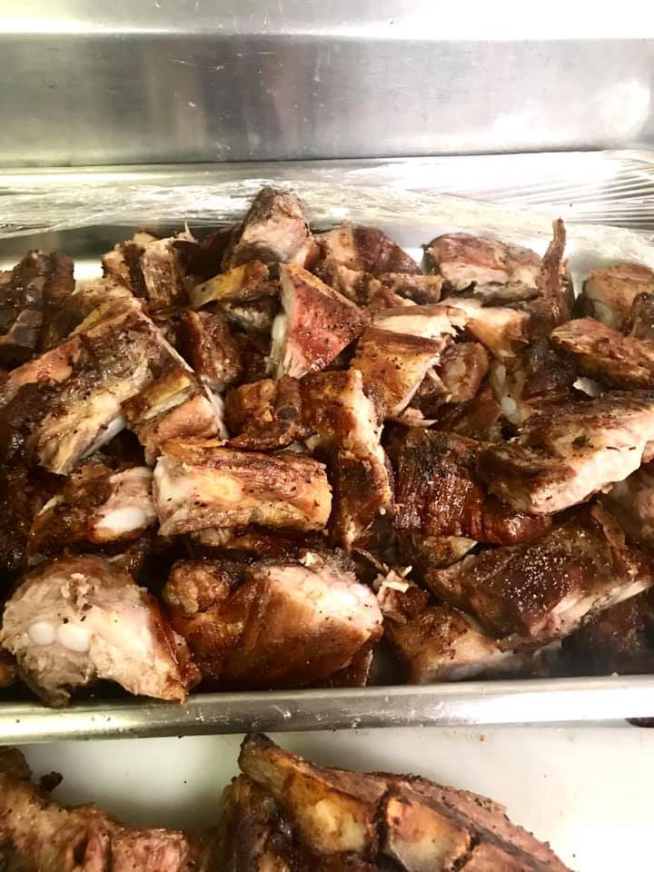 Many pieces of goat meat are in a metal container in the Stango Cuisine kitchen. Photo by Stango Cuisine.