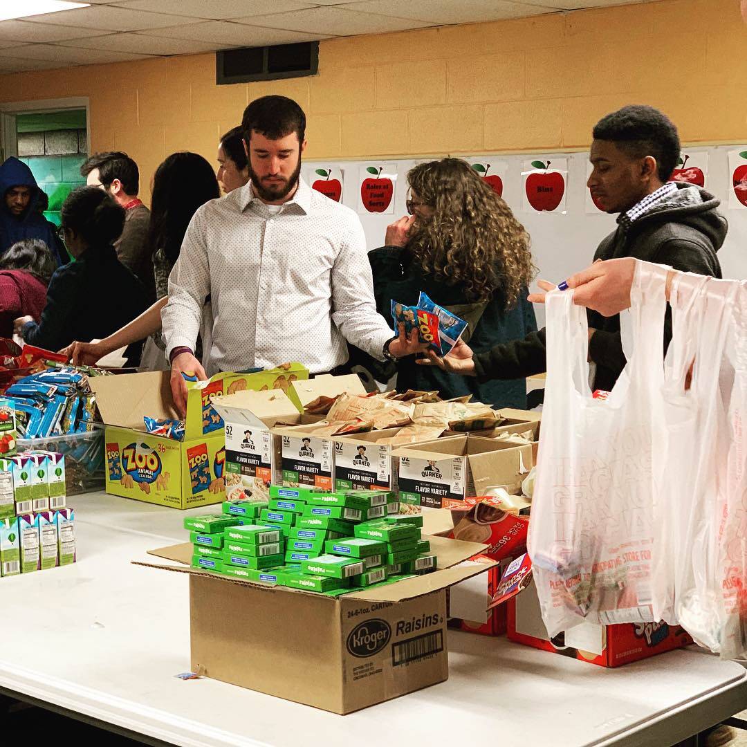 Male volunteers help to assemble bags of snacks for food insecure children in Chamaign. Photo provided by Feeding Our Kids.