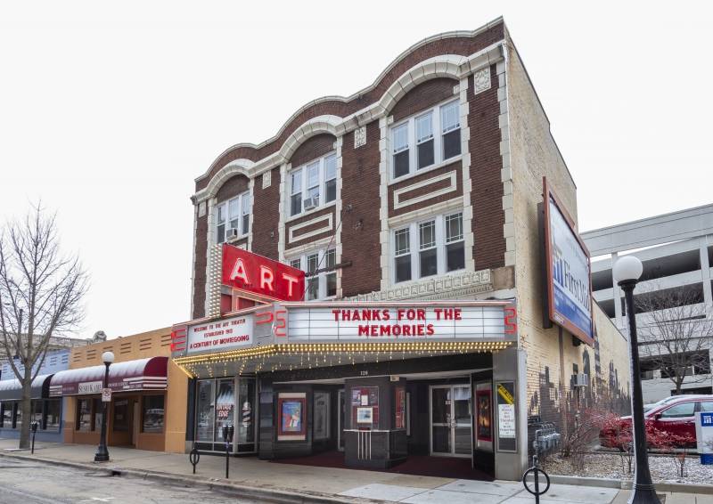 The facade of a theater with dark brown bricks and white detailing. There is a red sign with white lettering that says ART. Below the sign is a marquee that says Thanks for the Memories in red letters. Photo by Matt Wiley.