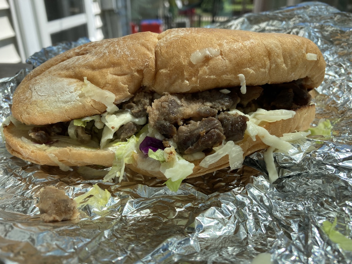 A large steak torta from Maize Mexican Grill is overflowing with steak and lettuce on a sheet of tin foil. Photo by Anthony Erlinger.