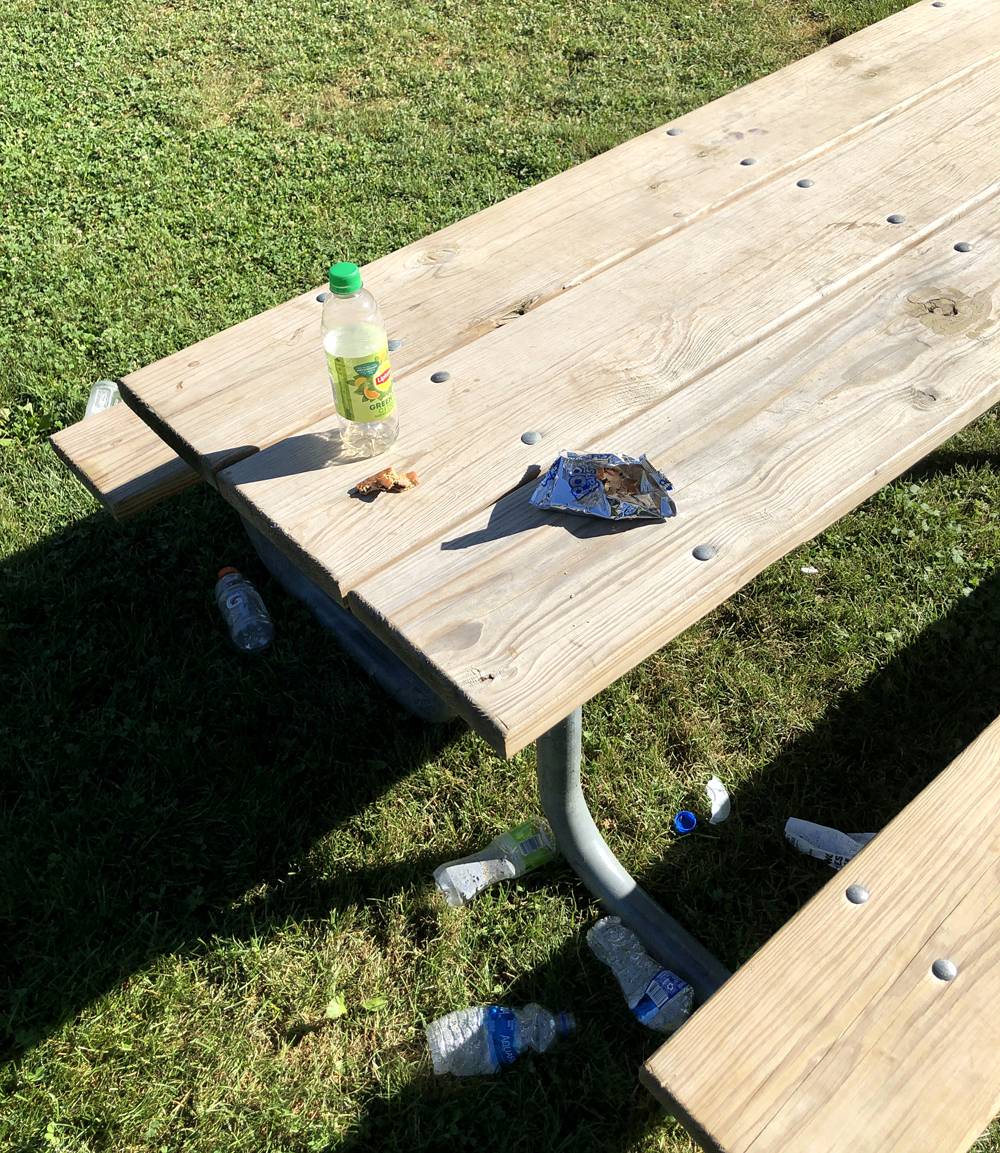 Empty bottles and other garbage sits on a picnic table at Clark Park in Champaign. There are a number of empty bottles underneath the table. Photo by Jessica Hammie. 