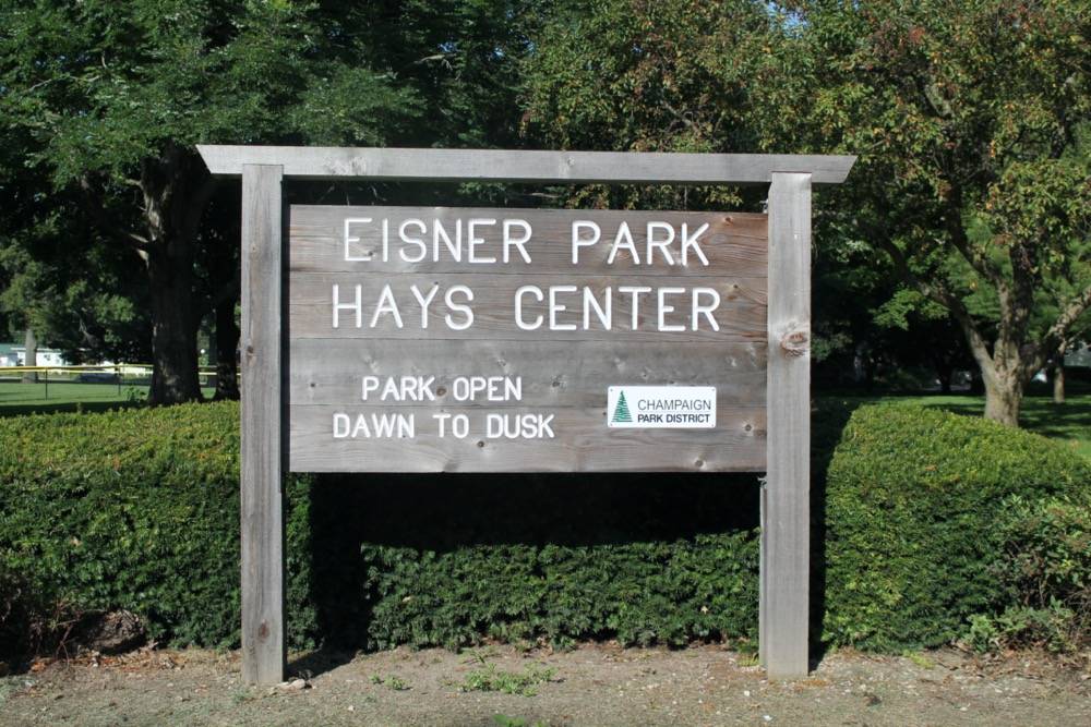 A brown wooden park sign that says in capital letters EISNER PARK HAYS CENTER. Photo by Maddie Rice.