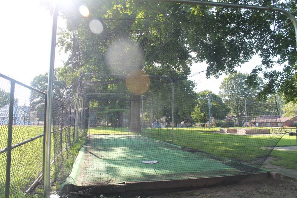A fence borders on the left of a batting cage 