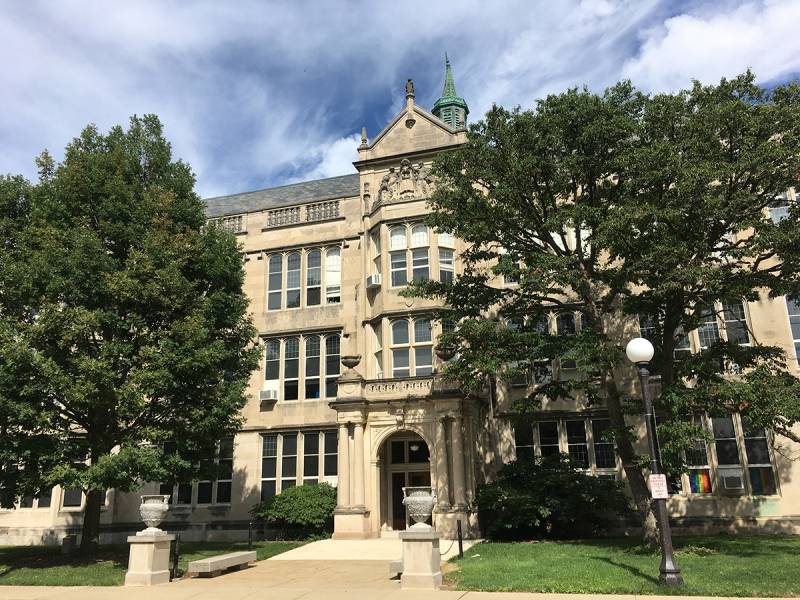 University High School, taken facing east from Mathews Street. Three story stone Gothic Revival building with multiple facing windows, decorative roof structures. Photo by Rick D. Williams.