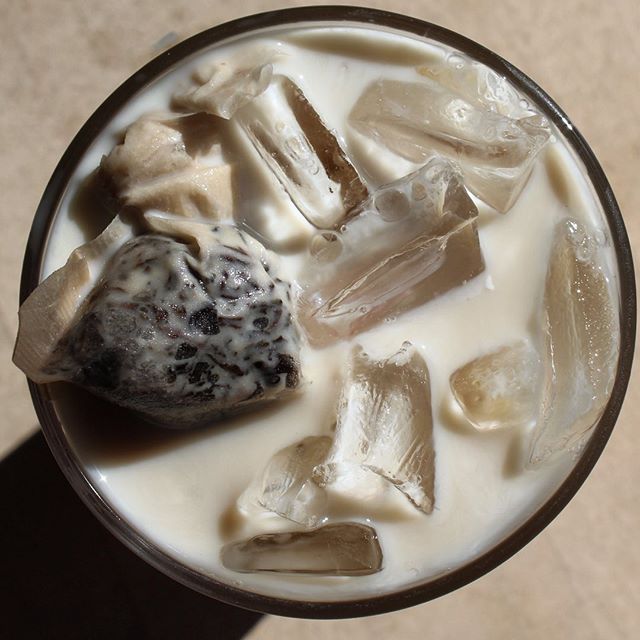 An overhead photo of a white drink with ice on a sand colored counter. Image from Cafe Kopi's Instagram.