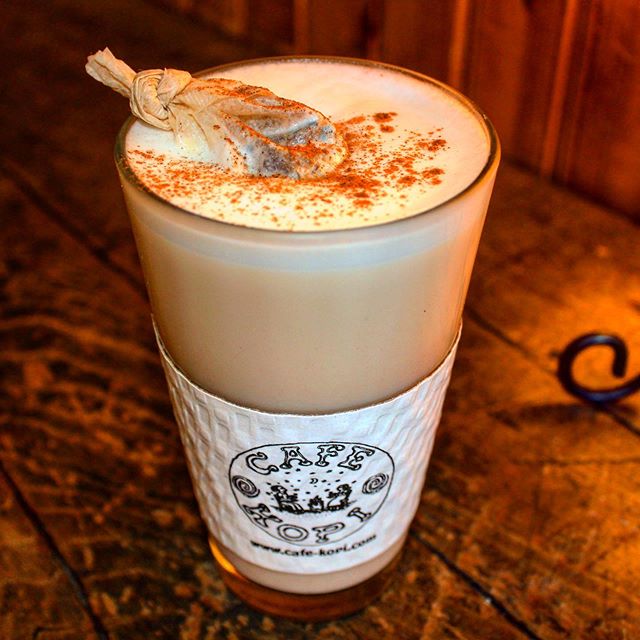 A light brown coffee drink in a glass pint glass with a paper sleeve reading Cafe Kopi. Image from Cafe Kopi's Instagram.