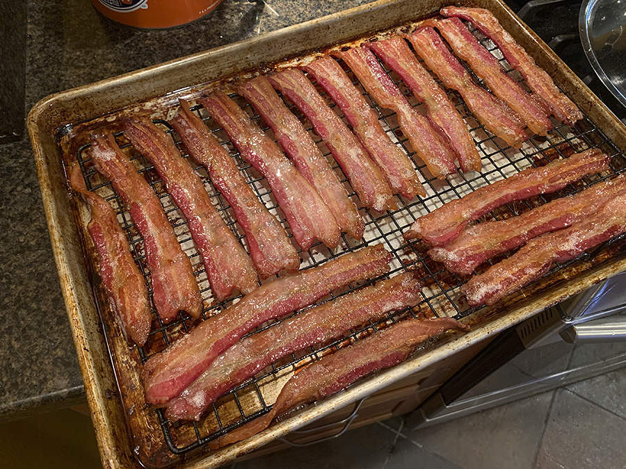 A photo of sliced bacon, cooked, on a metal cooking rack on a baking sheet in the author's home. Photo by Zoe Valentine.