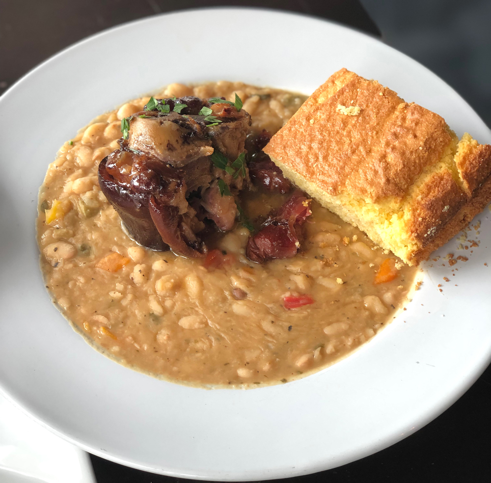 A plate of rice gumbo with a side of cornbread from Champaign's Wood N' Hog on a white plate. Photo by Jessica Hammie.