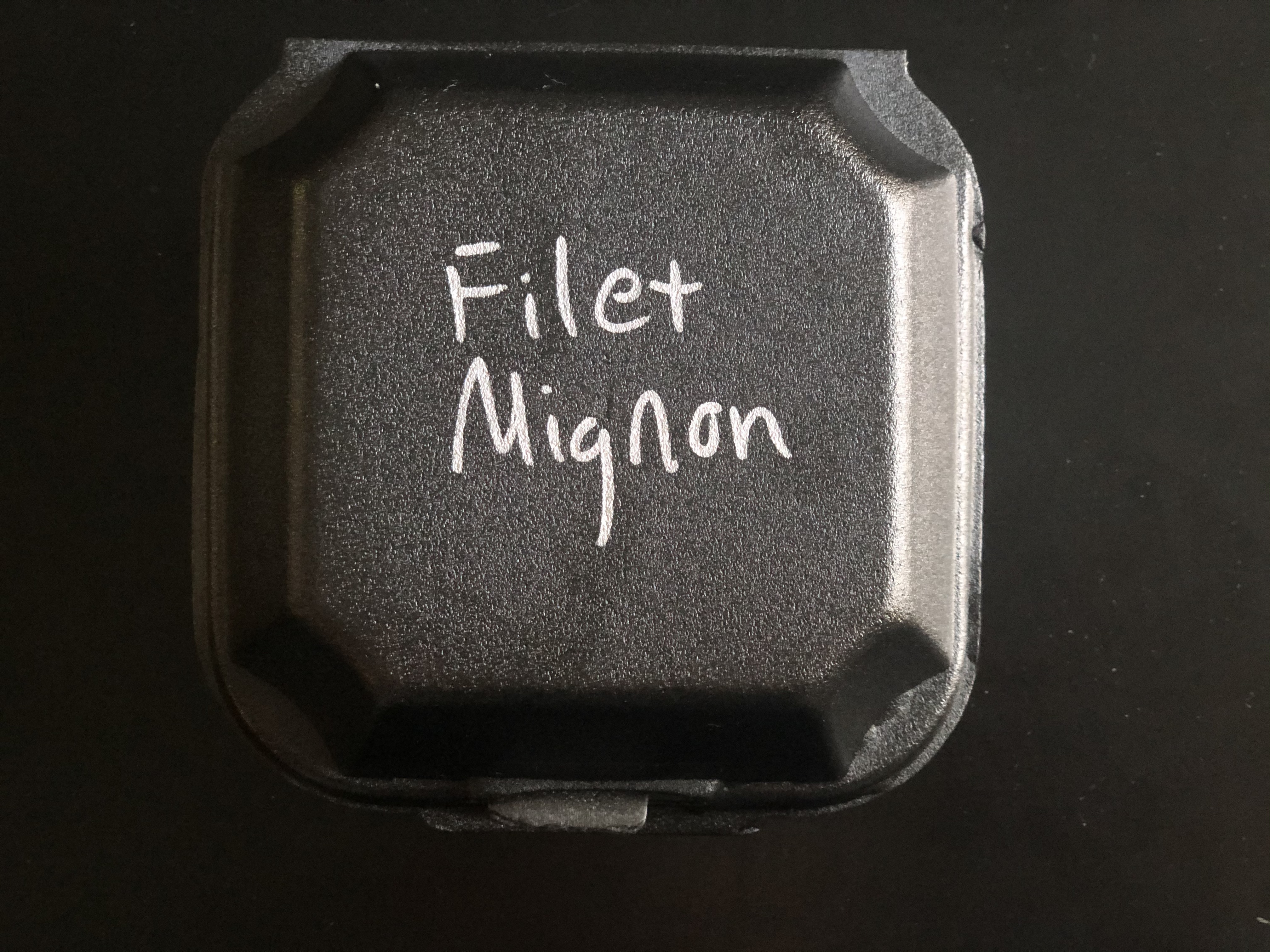 A small square black styrofoam container reads 