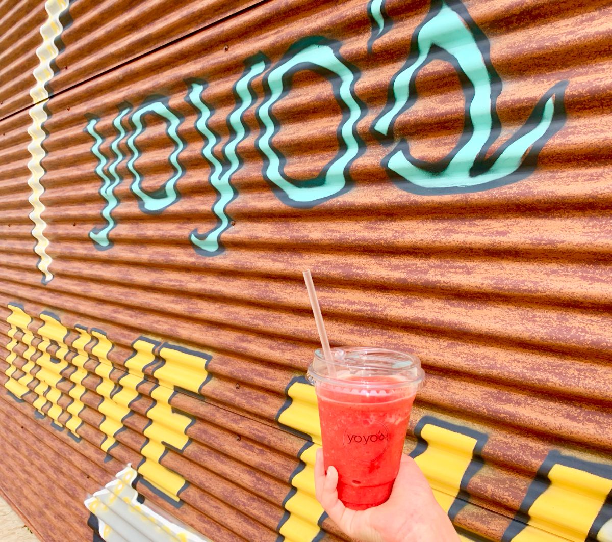Strawberry smoothie in a plastic to go cup with no straw in front of Yoyo's sign. Photo by Stephanie Wheatley.
