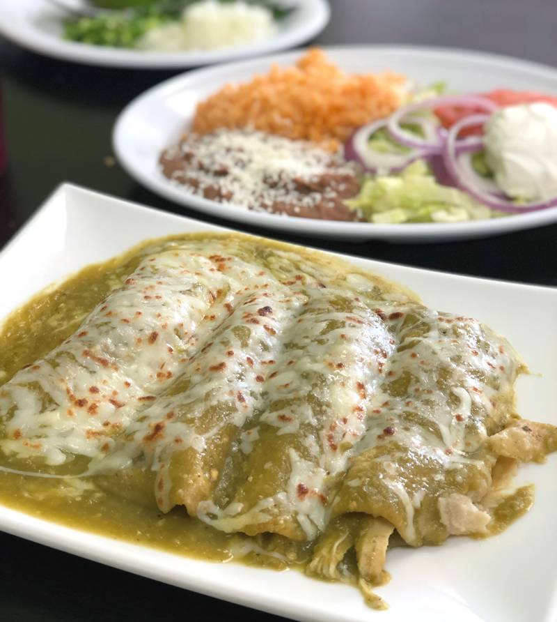 Chicken enchiladas verde on a white plate with rice at La Mixteca. Photo by Jessica Hammie.