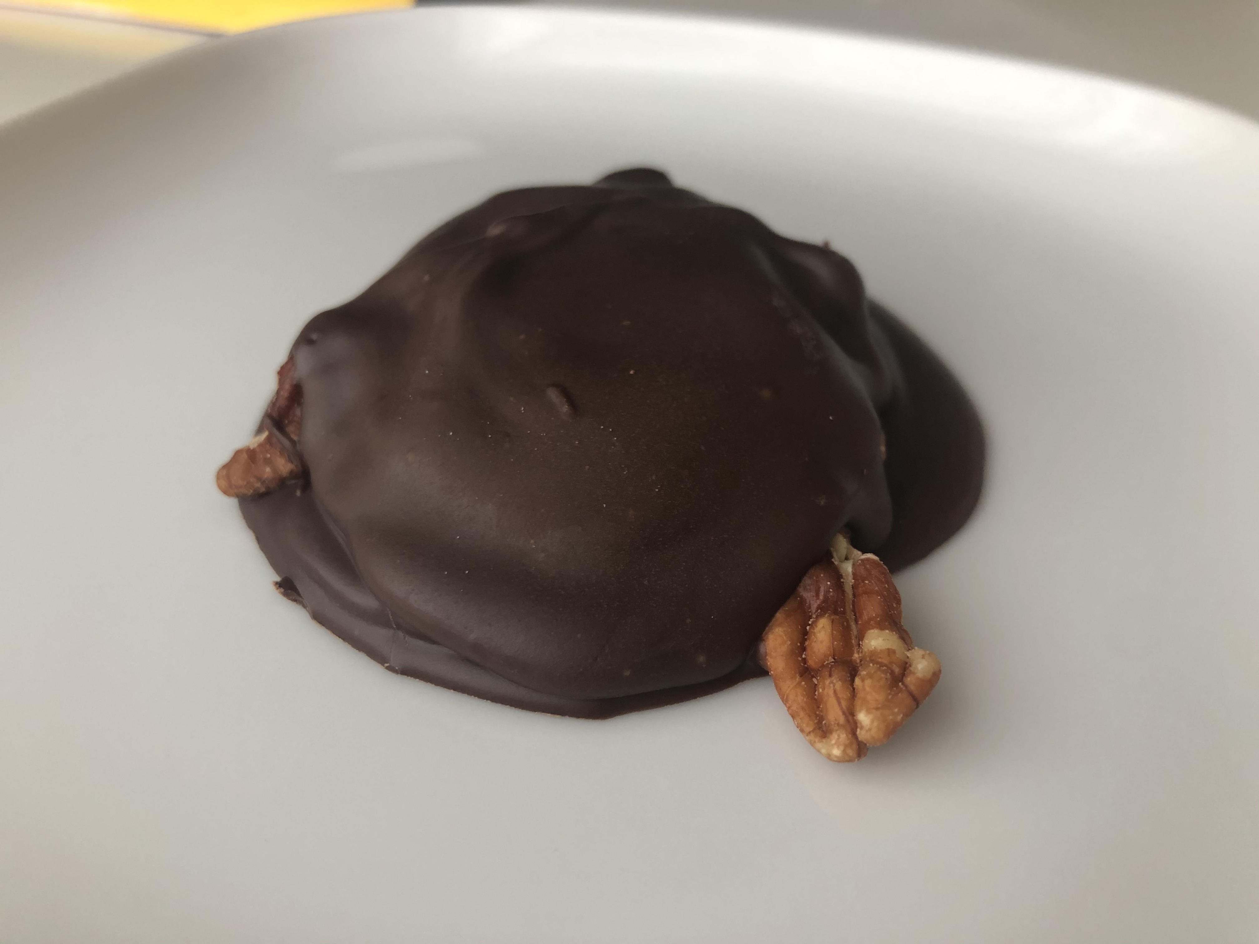 A single turtle with a large pecan sticking out of the hardened milk chocolate turtle by Sugga Shaii Sweets. Photo by Alyssa Buckley.