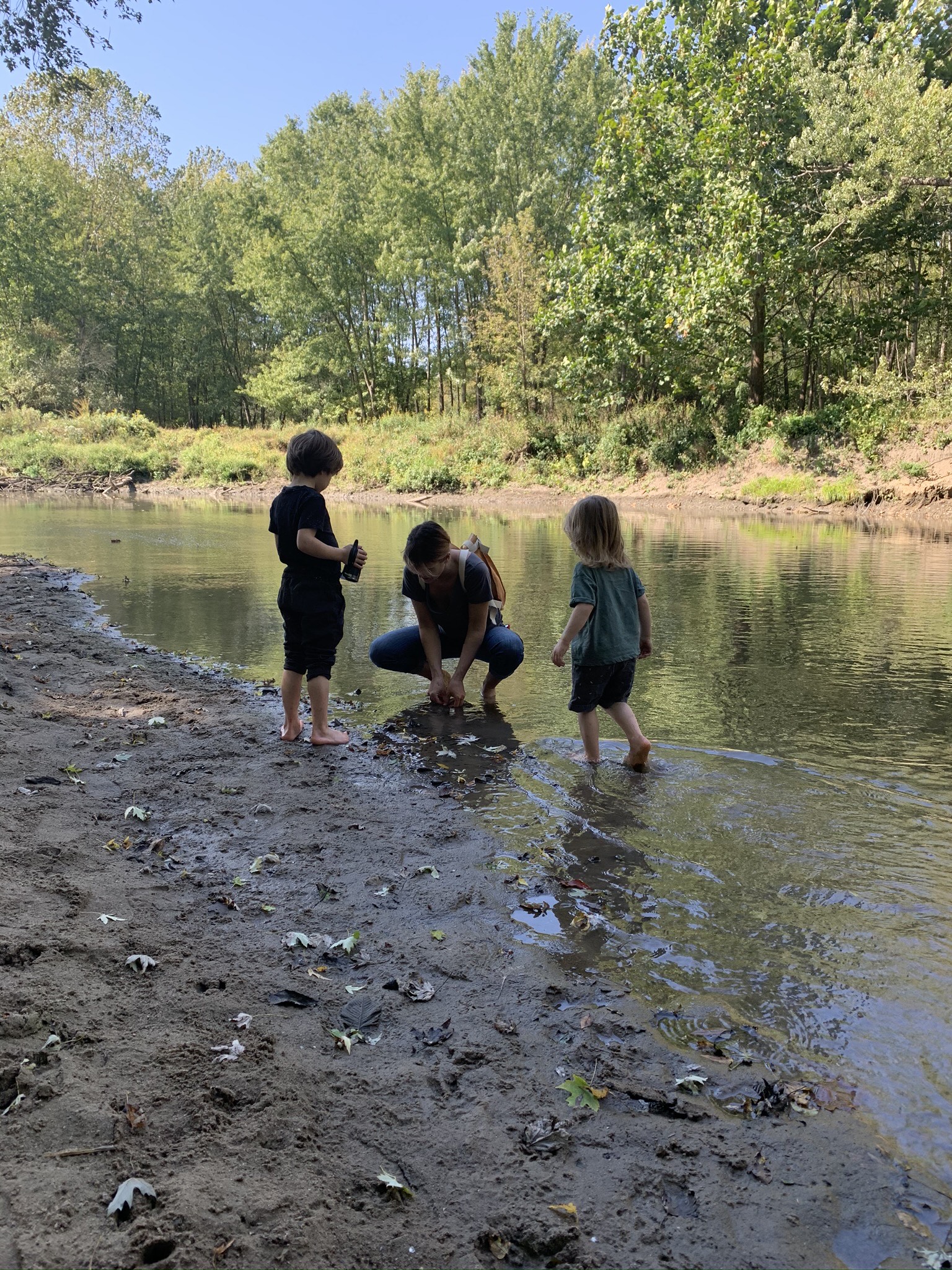 Two children and their mom play in the salt fork river