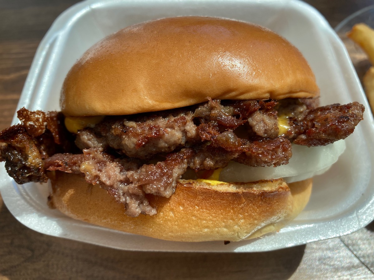 A double cheeseburger from Bobo's Barbeque is in a white styrofoam container. The meat and cheese are sandwiched between a plain bun. Photo by Anthony Erlinger.