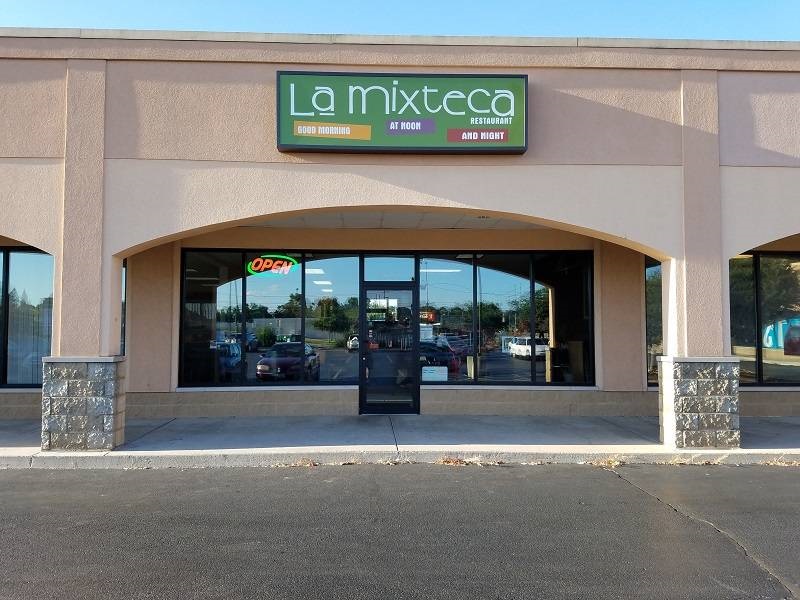 The entrance of La Mixteca with a glass door set near a front of glass windows. Photo by Matthew Macomber.