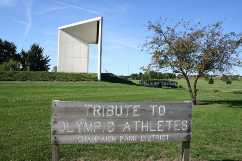 a large white monolithic sculpture sits behind a sign stating Tribute to Olympic Athletes