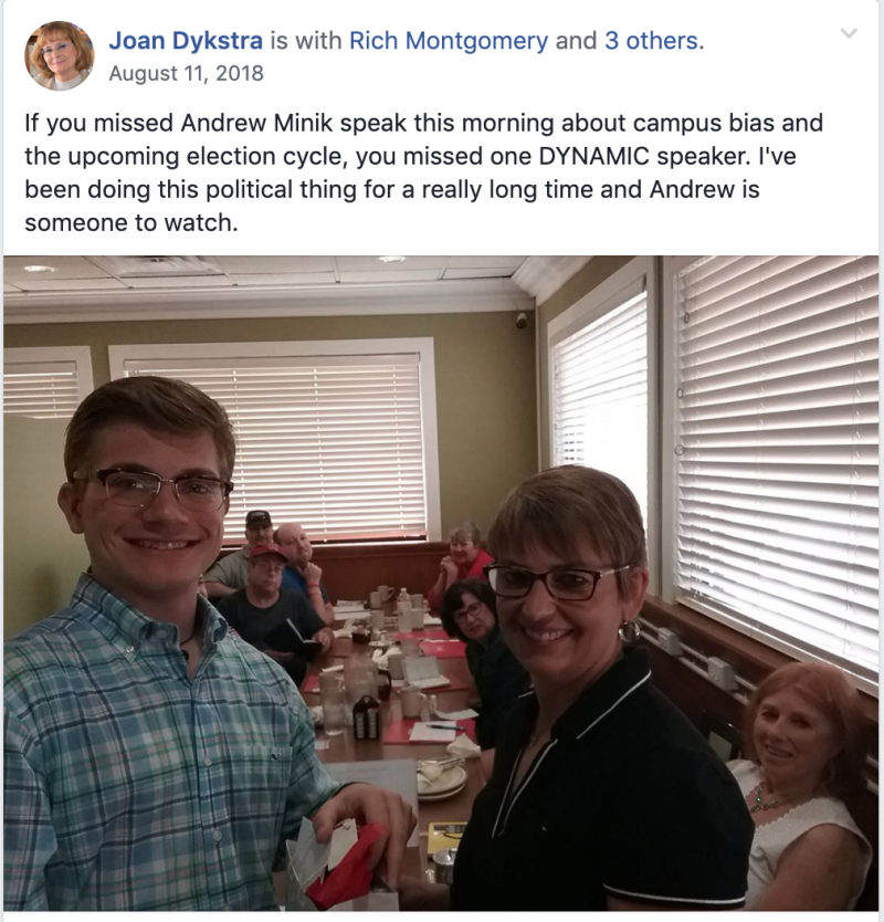 Screenshot from Joan Dykstra's Facebook post on August 11, 2018 wherein she speaks about how Andrew Minik is a dymanic speaker. A photo of Minik and another woman is below the text. Behind them a group of people are seated at a long table in a restaurant.