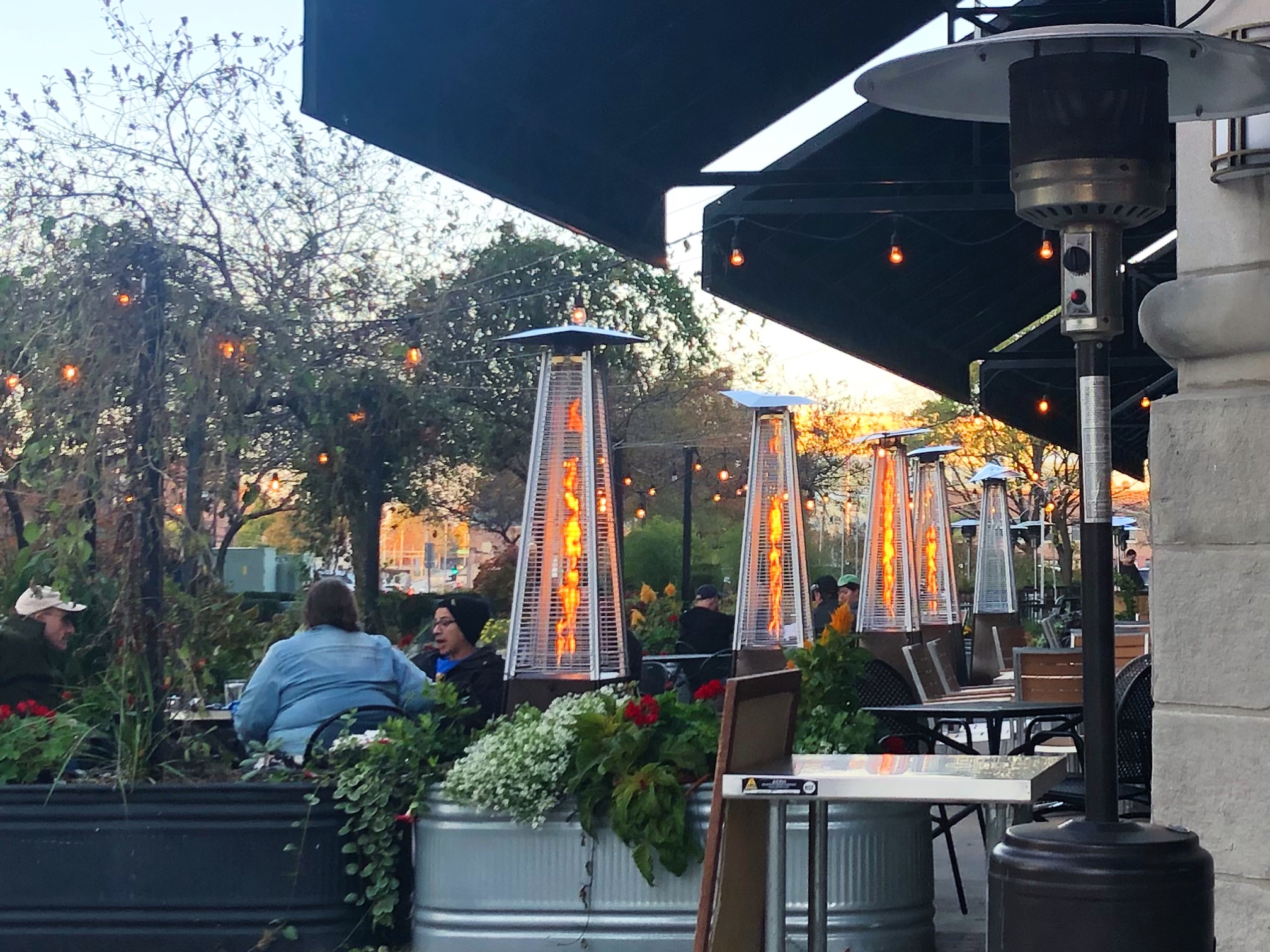Outside of Big Grove Tavern, there are tables set up spaced apart and a row of lighted flame heaters. Photo by Alyssa Buckley.