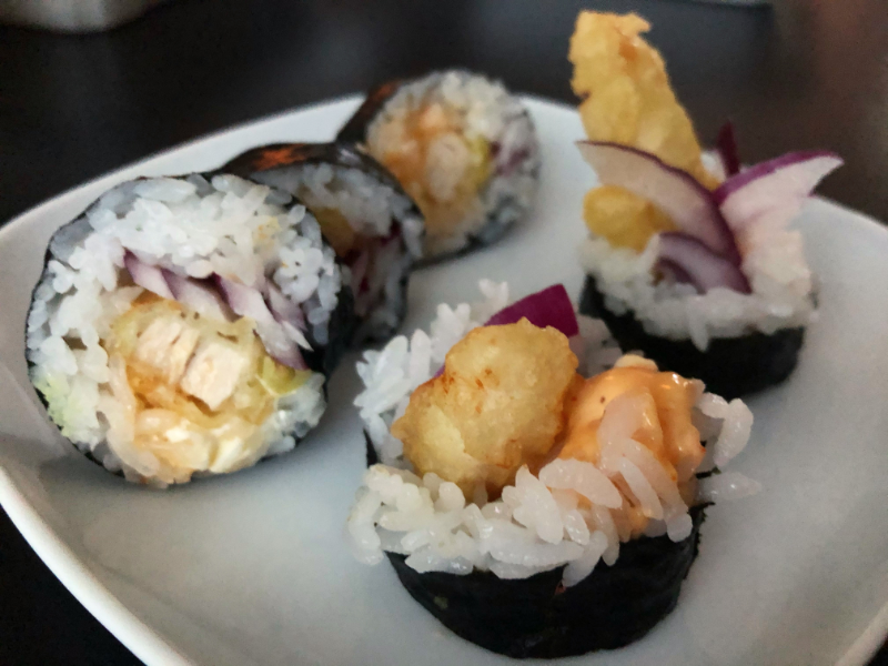 Five sushi pieces from the Chicken Run roll from Sushi Kame are on a white plate. Photo by Alyssa Buckley.