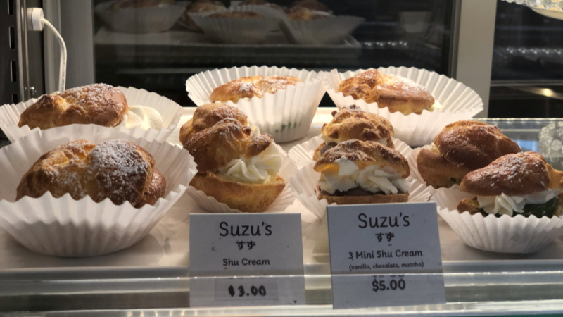 Several cream filled baked goods sit in white papers inside a glass case at Suzu's Bakery. Photo by Alyssa Buckley.