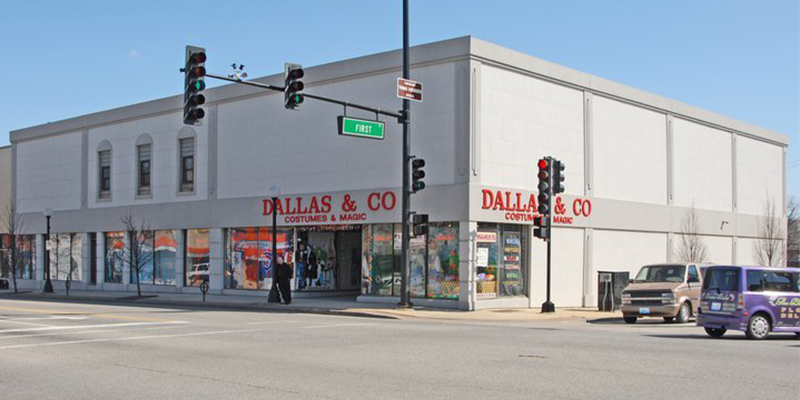 View of Dallas & Company from across the street. There are street lights and cars at the intersection.