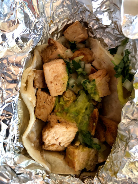A chicken taco with guacamole on top in a tin foil wrapper. Photo by Remington Rock.