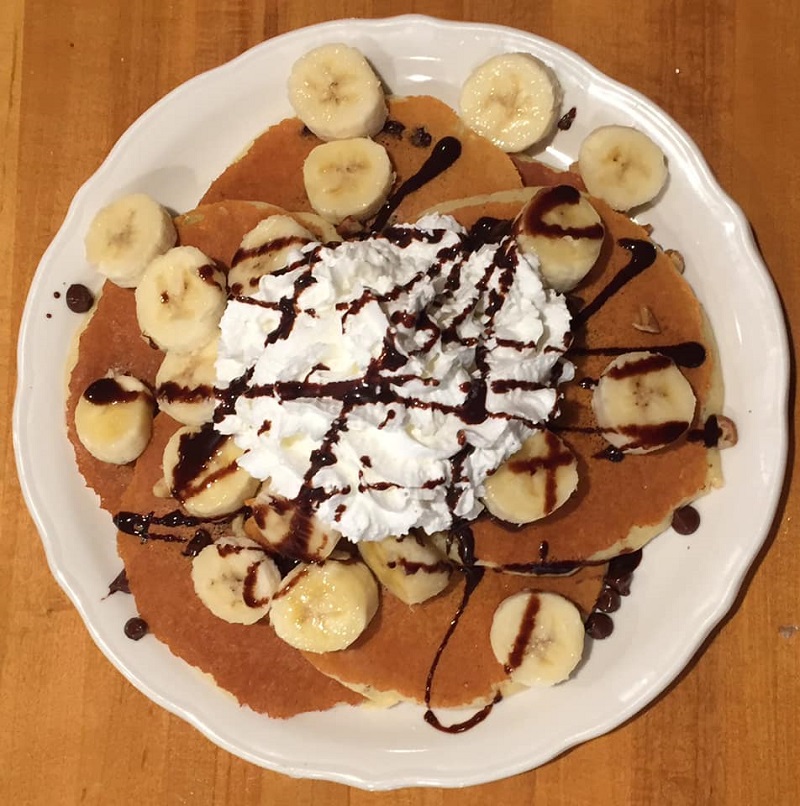Pancakes filled with chocolate chips and topped with bananas, whipped cream, and a chocolate drizzle. Photo courtesy of Original Pancake House in Champaign.