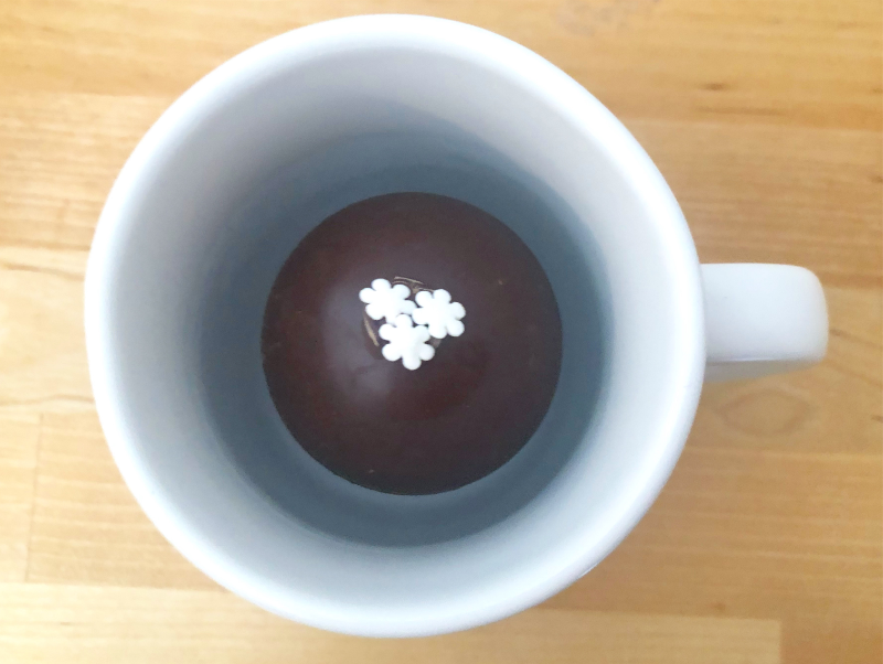 A hot chocolate bomb sits inside a white coffee mug. Photo by Alyssa Buckley.