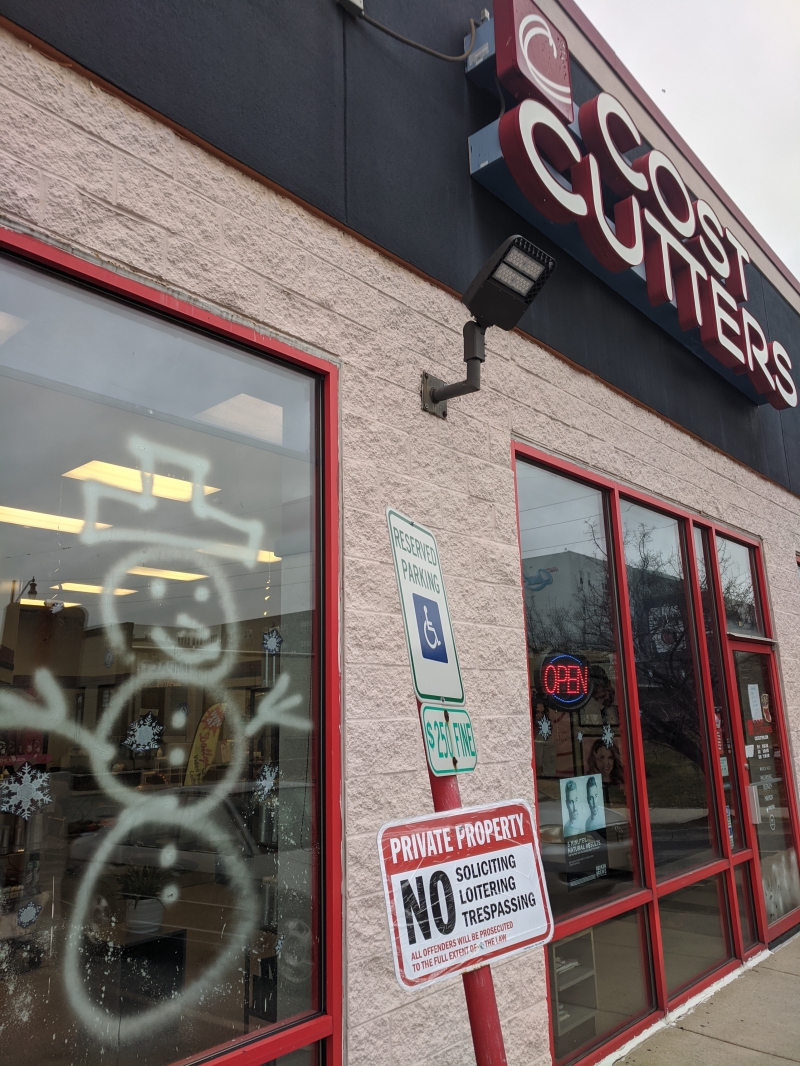 The store front of Cost Cutters. A window has a basic snowman outline spray painted in white. Photo by Tom Ackerman.