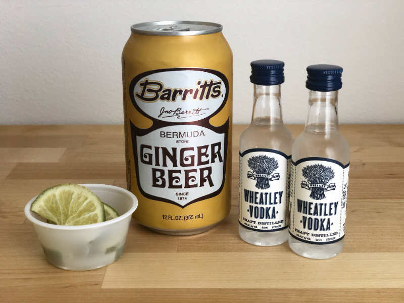 An American mule drink kit sits on a butcher block counter. There is a mini cup of lime slices, a ginger beer, and two mini bottles of Wheatley vodka. Photo by Alyssa Buckley.