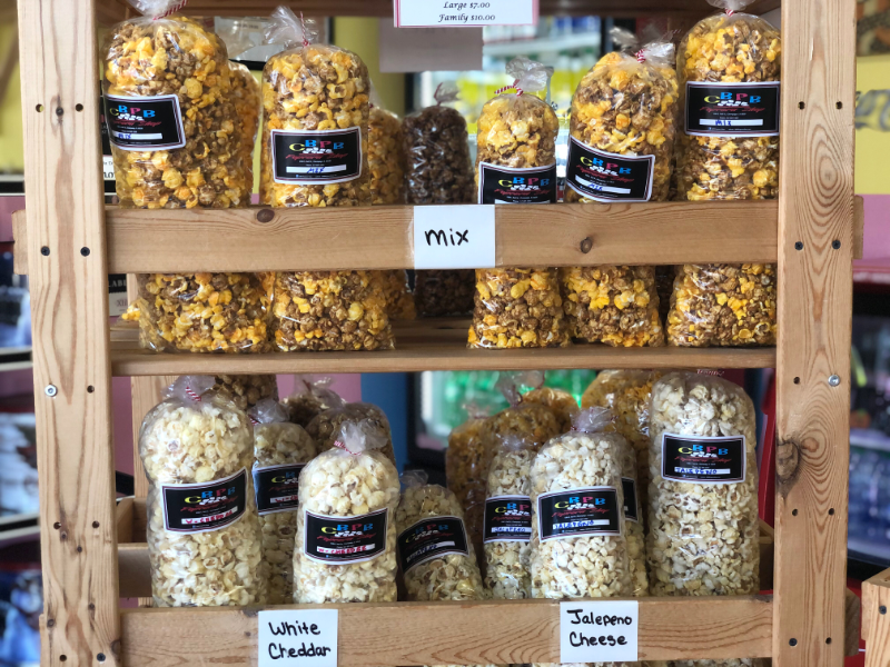 In the Cool Bliss Pop Bliss store in Champaign, many bags of many flavors of popcorn are on a wooden shelf. Photo by Alyssa Buckley.