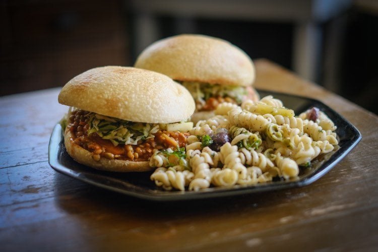 Two vegetarian sandwiches sit on a plate with a side of pasta salad on a brown table. Photo from Red Herring's Facebook page.