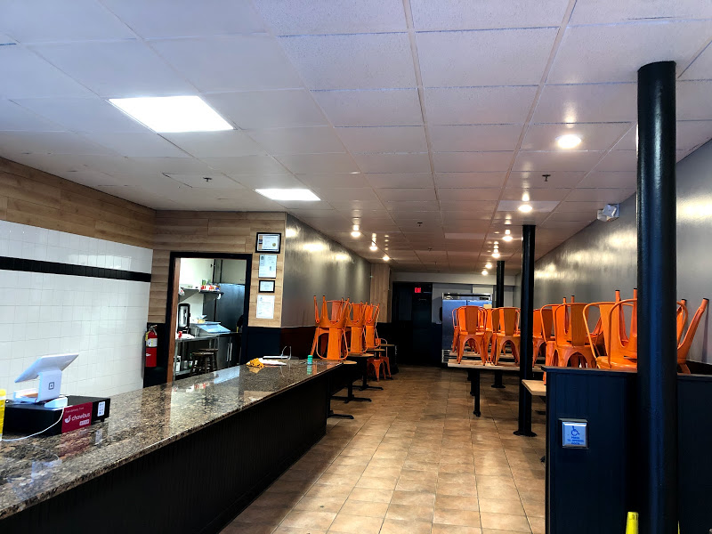 The interior of Taco Shack in Champaign is empty. There is a long counter on the left and several tables on the right with orange chairs stacked up tall. Photo by Remington Rock.