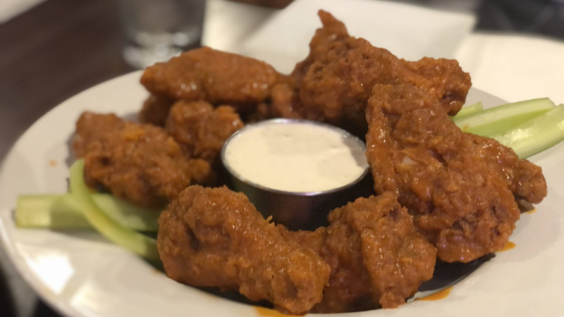 A dozen Buffalo wings sit on a white plate at Crane Alley in Urbana. In the center is a cup of ranch dressing. Photo by Alyssa Buckley.