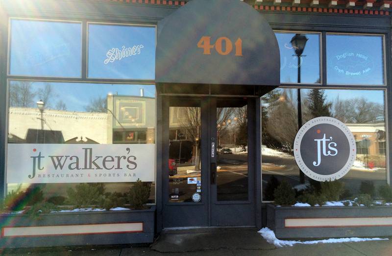 An exterior view of JT Walker's restaurant in Mahomet, Illinois. The large glass windows reflect the the opposide side of the street. There is a large jt's logo on the right, and a large graphic of jt walker's on the left. Photo by Jessica Hammie. 