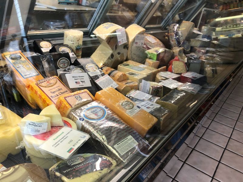 Inside Cheese & Crackers in Champaign, there is a cold case featuring lots of cheese to be sliced at request of customers. Photo by Alyssa Buckley.