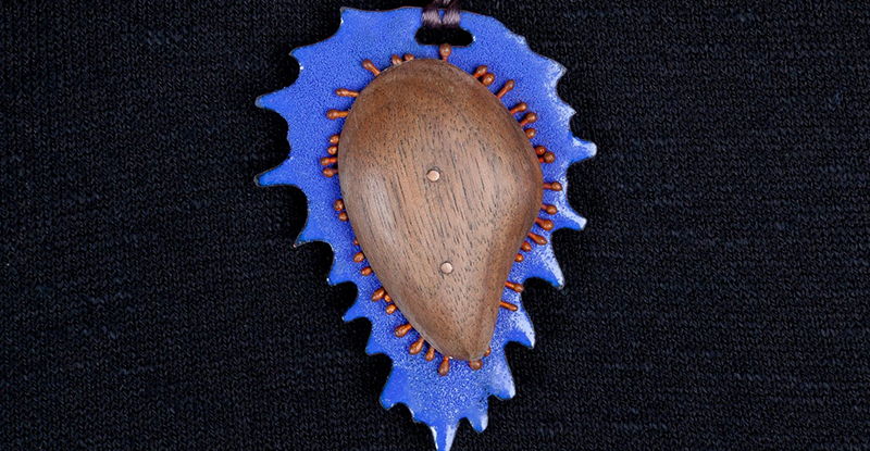 Close-up photo of handmade pendant featuring pointy organic purple shape with white center. Photo from Giertz Gallery Facebook page.