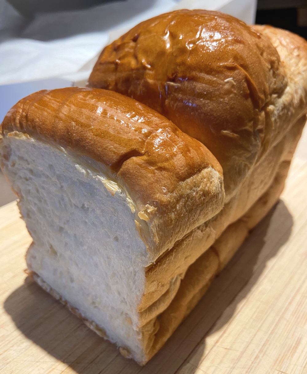 Shoku Pan from Suzu's Bakery in Champaign. A loaf of bread sits on a cutting board. The white interior is exposed. Photo by Jessica Hammie. 
