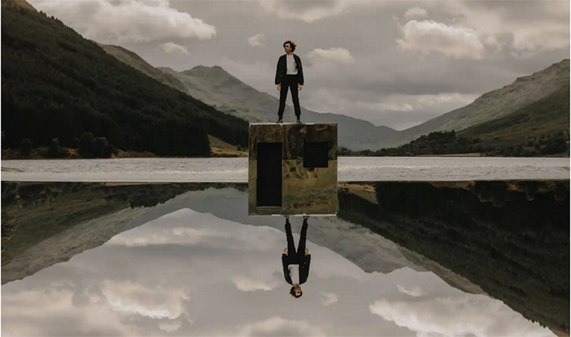 Scott Silven on standing on a block with image reflected in water in the Scottish Highlands. Photo from KCPA website.