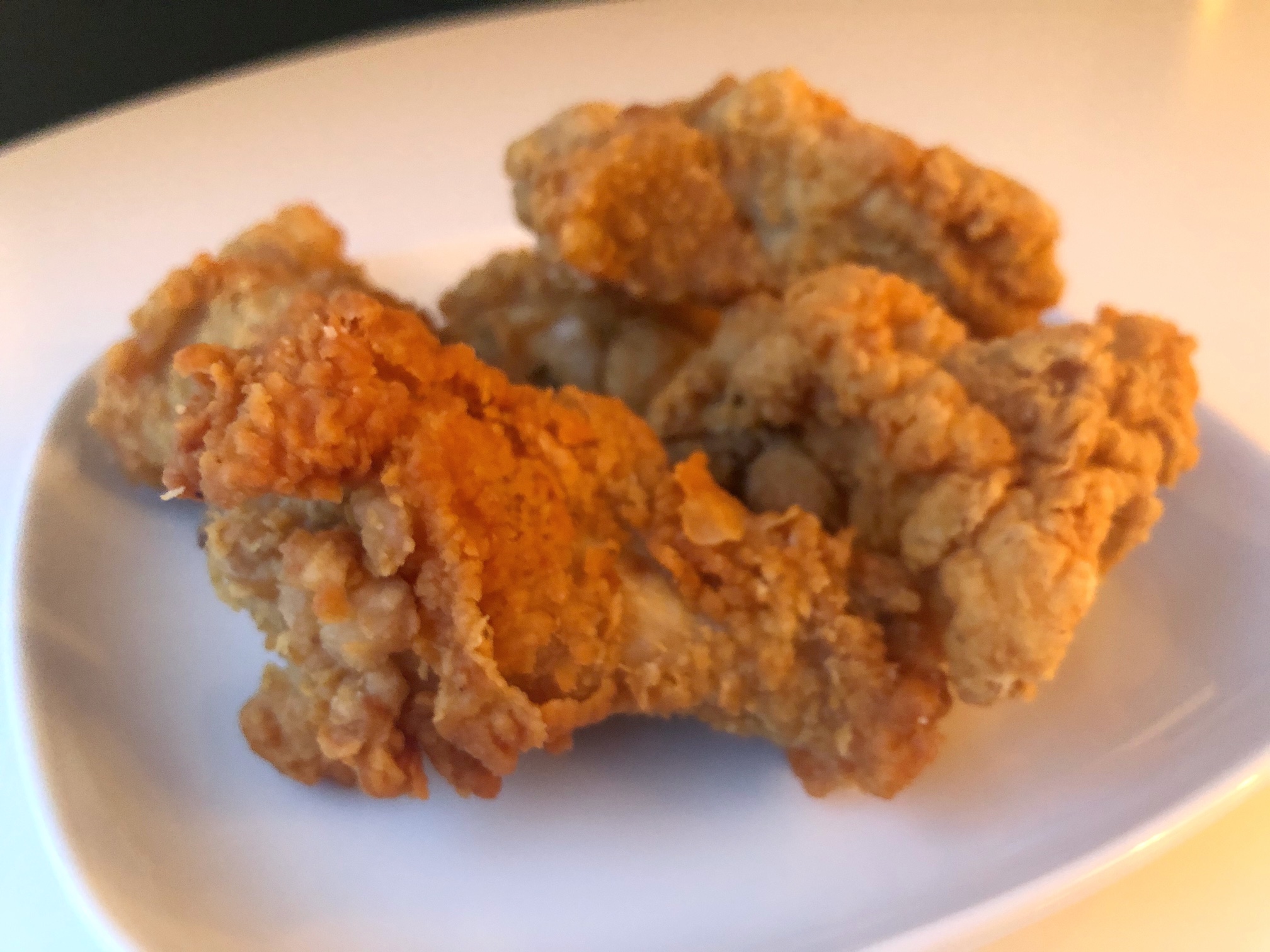 Five small chicken wings, breaded and golden brown, lay on a white plate. Photo by Alyssa Buckley.