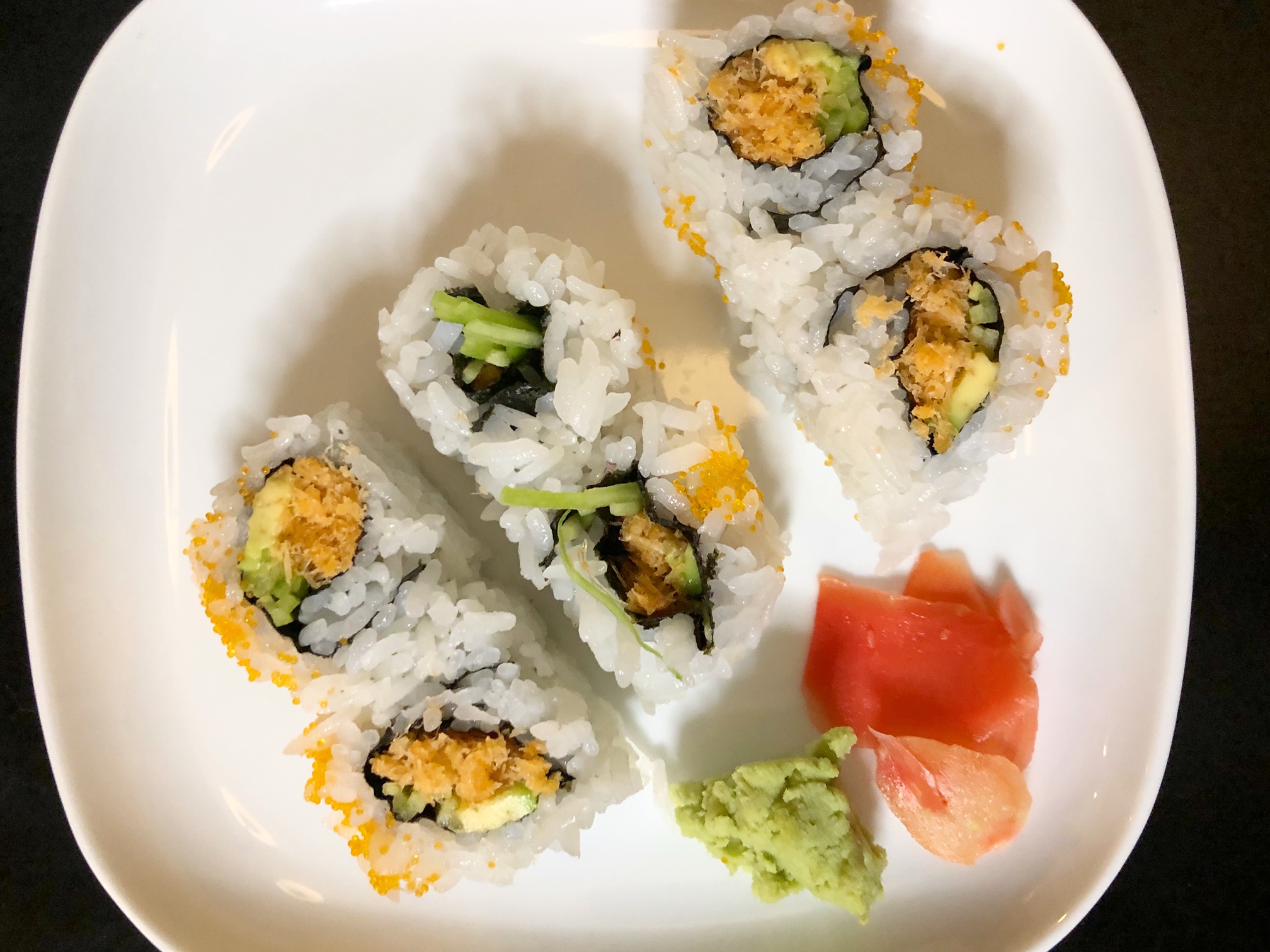 An overhead photo of the Canada roll from Sushi Kame shows six piece of urimaki. There are sticks of cucumber poking out and an light orange crab salad. Photo by Alyssa Buckley.