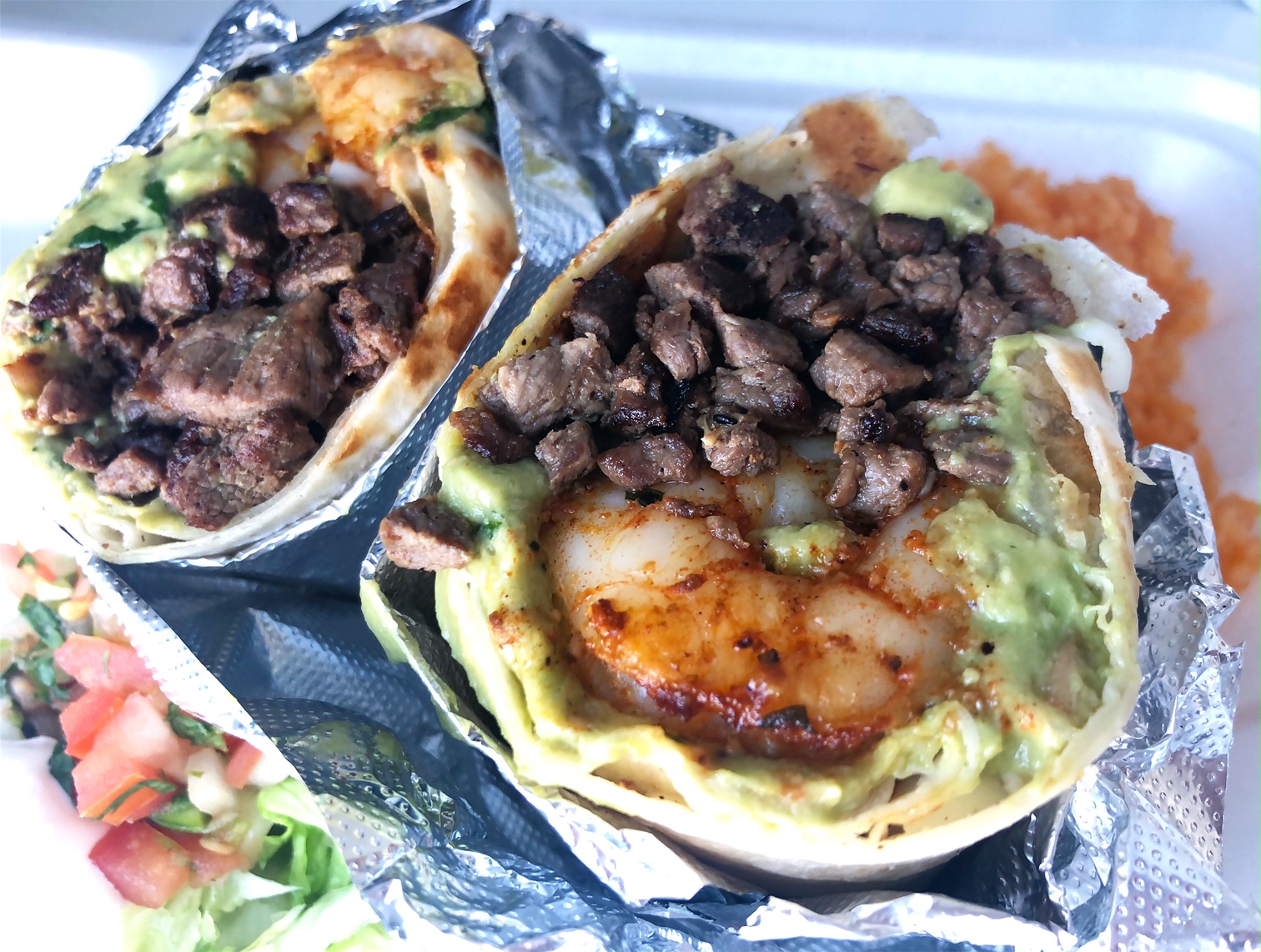 A burrito sliced in half shows shrimp and chopped steak with a generous amount of guacamole. Photo by Alyssa Buckley.
