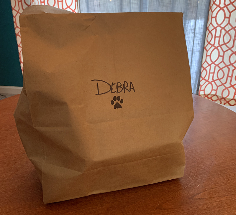 Photo of take-out brown bag with paw print and the name Debra. Photo by Debra Domal. 