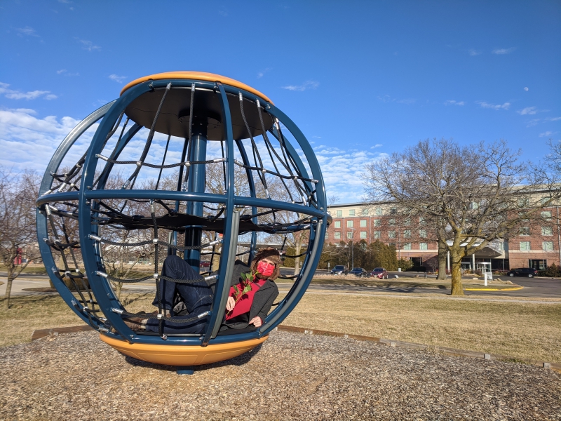 The writer is laying on his side, inside the round play structure, with one leg knee propped up. Photo by Andrea Black.