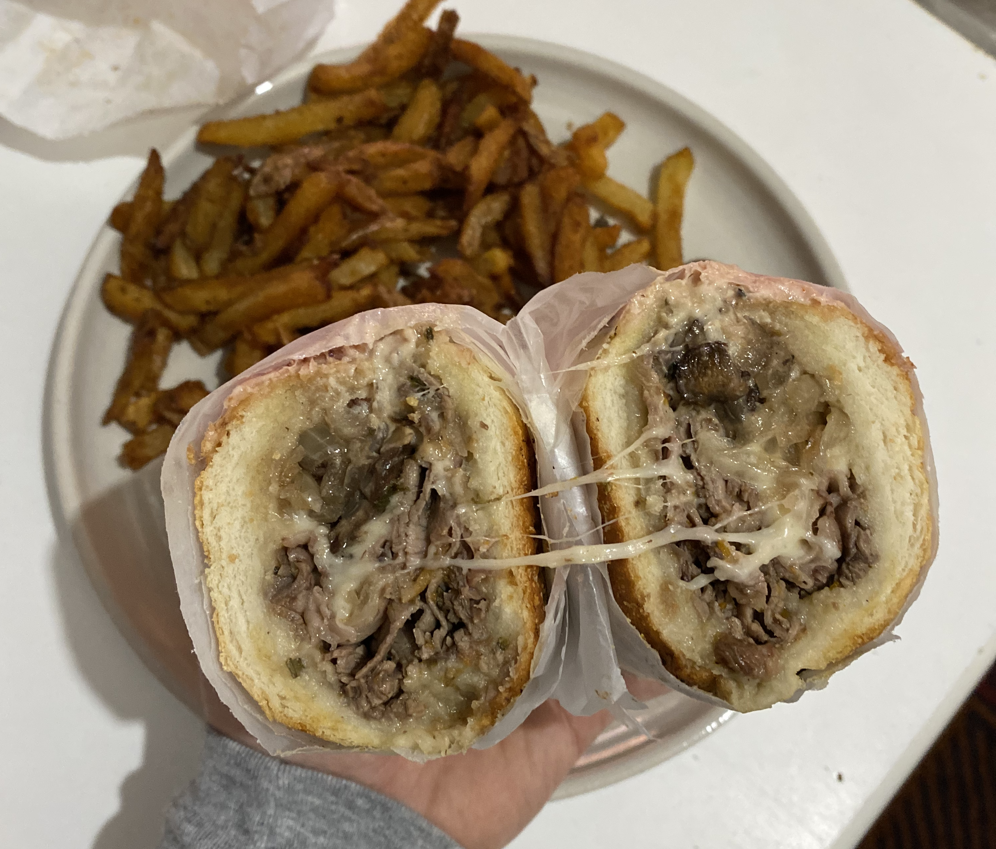 An overhead shot of the Wednesday RW 2021 sandwich special Roast Beef & Swiss shows the sandwich cut in half with cheese stringy and melting between them with a side of fries. Photo by Patrick Singer.