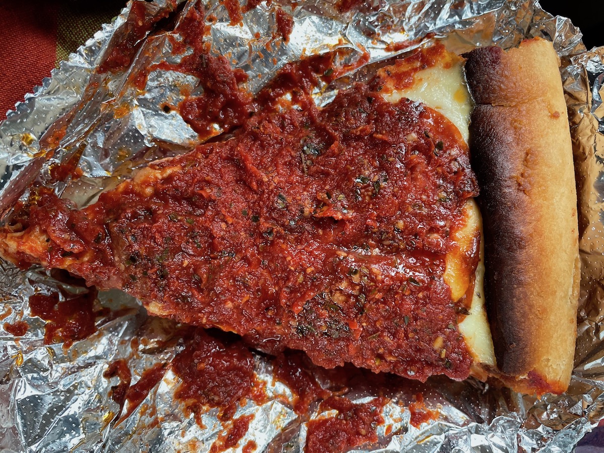 A slice of deep dish pizza from Papa Del's sits on a tin foil piece. Photo by Anthony Erlinger.