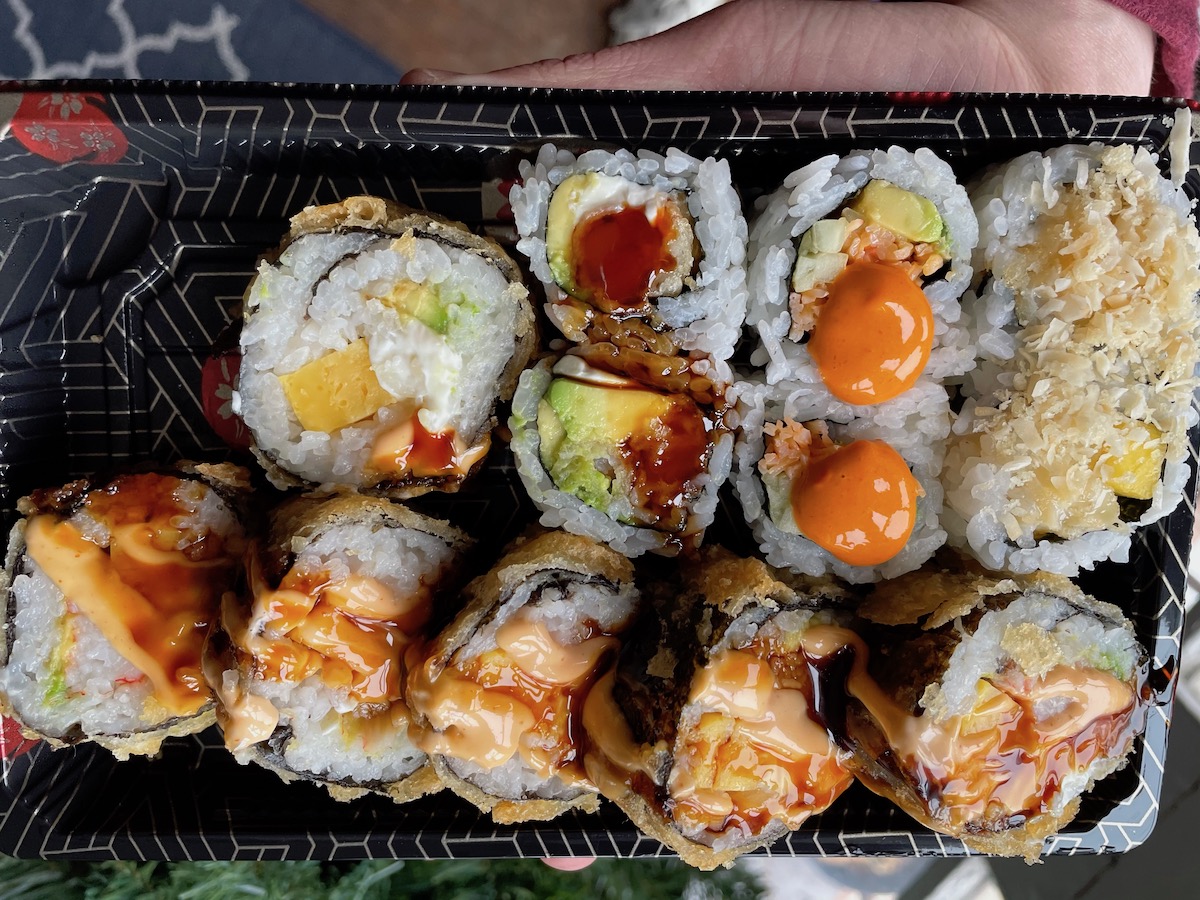 Dollar rolls from KoFusion are in a black rectangular takeout container. Photo by Anthony Erlinger.