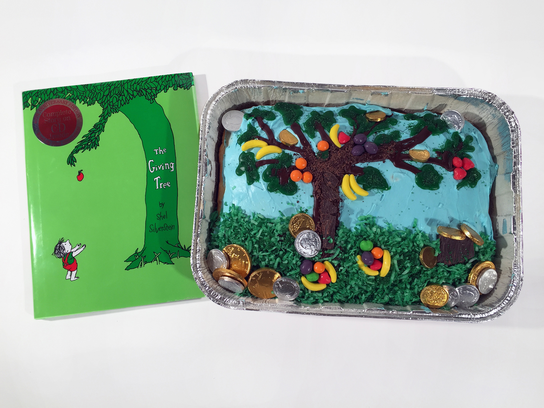 A cake from the Edible Book Festival hosted by the University Library celebrates The Giving Tree with a sheet pan cake decorated with candy fruit and money. Photo from the University of Illinois Library's website.