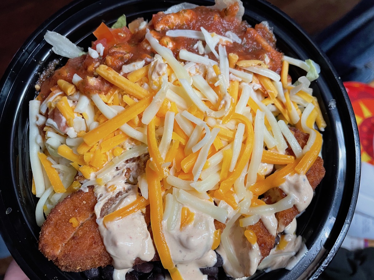 A photo of Cactus Grill's fish burrito bowl with shredded cheese, lettuce, salsa, rice, and fried fish. Photo by Anthony Erlinger.